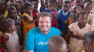 UNICEF-Nothelfer Danile Timme sitzt auf dem Boden, umgeben von Kindern. 
