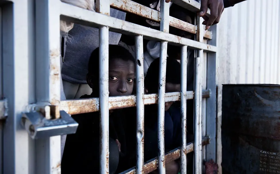 Kinder werden vielfach mit Erwachsenen in überfüllten Zellen gemeinsam eingesperrt. | UNICEF/Romenzi Ein Junge in einem Gefängnis in Libyen.