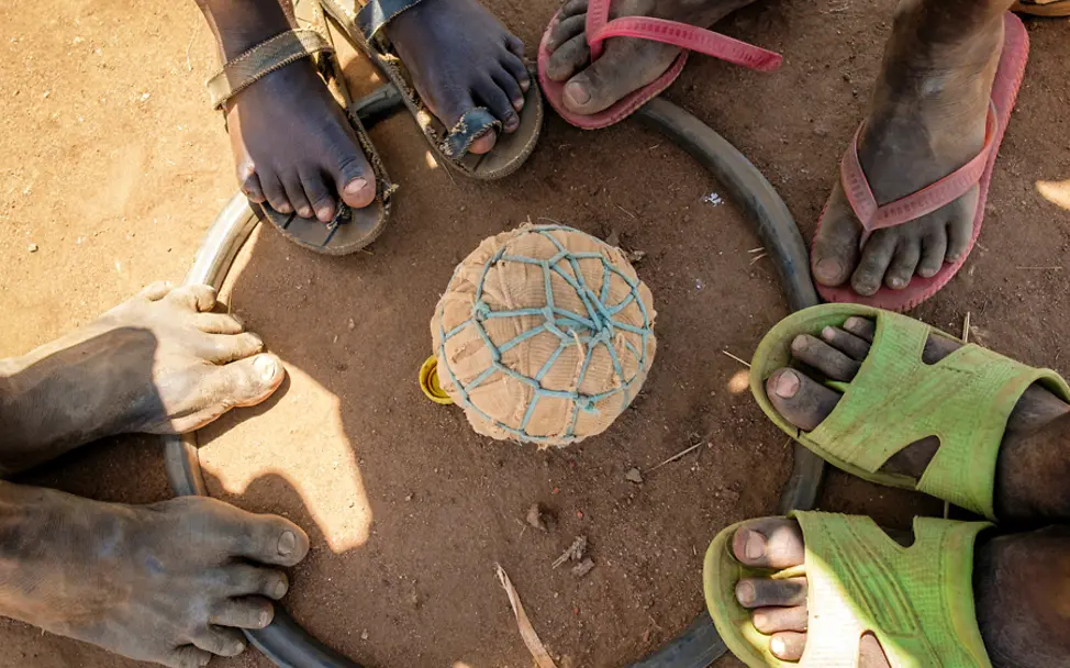 Kinder in Uganda stehen um einen selbstgemachten Fußball | © UNICEF/Ose Uganda: Kinder stehen um einen Fußball der aus Lumpen gemacht wurde