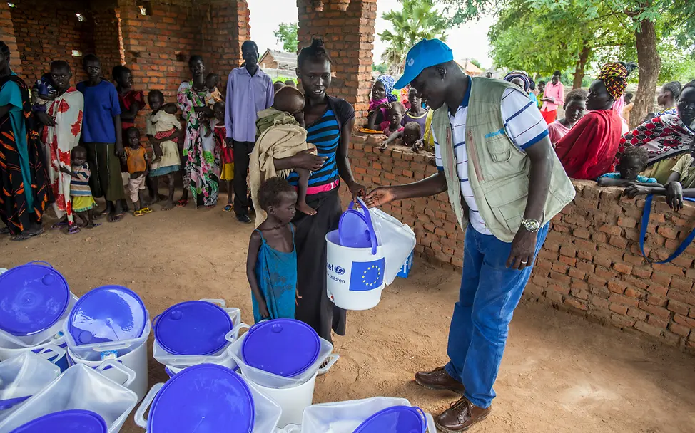 Hilfsgüter gegen Cholera im Südsudan: Ein UNICEF-Helfer verteilt Wassereimer an eine Familie. 
