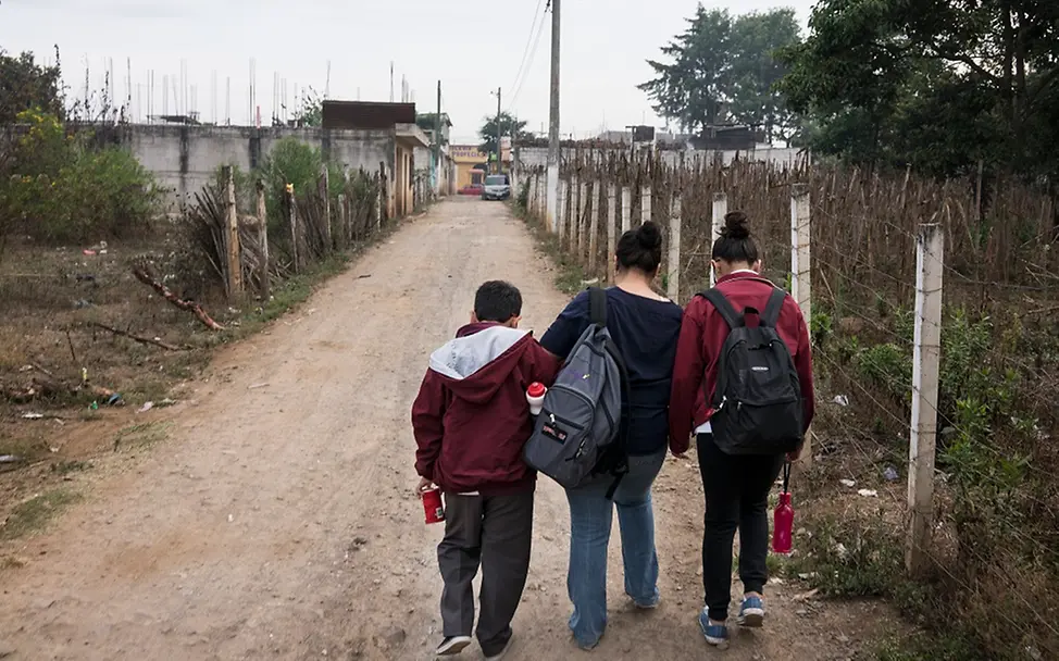 Zurück in der Heimat: Mary und ihre Kinder | © UNICEF/Bindra Eine unbefestigte Straße in Guatemala: Eine Mutter bringt ihre beiden Kinder zur Schule