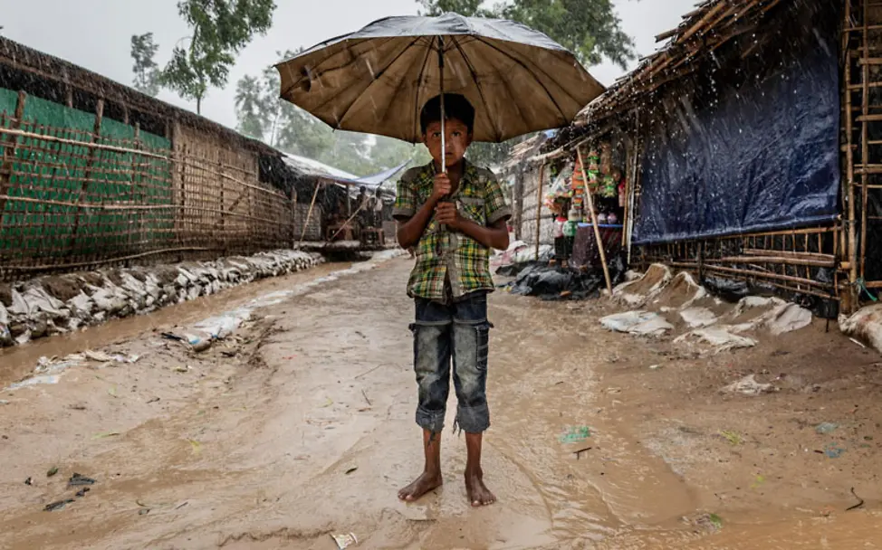 Rohingya: Ein Junge im Flüchtlingscamp unter einem Schirm | © UNICEF/Brown Rohingya: Ein Junge steht im Flüchtlingscamp unter einem Schirm