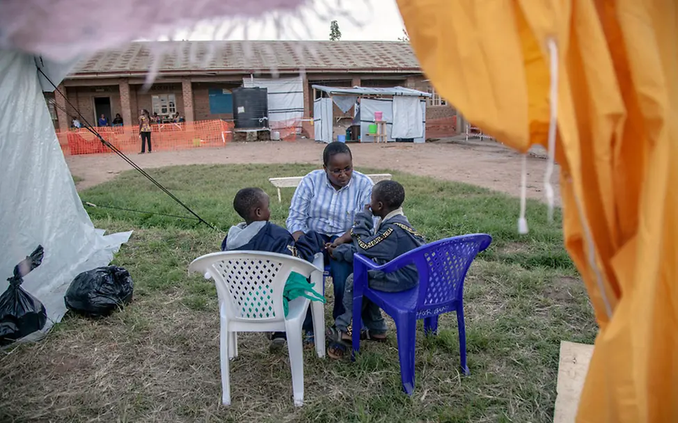 Eine UNICEF-Helferin spricht mit zwei Jungen, die aus dem Krankenhaus entlassen wurden. | © UNICEF/Naftalin Ebola im Kongo: UNICEF-Helfer unterstützen Kinder nach der Ebola-Behandlung