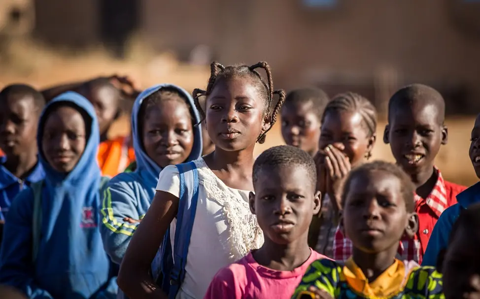 Nabyla, 13, wartet mit ihren Mitschülern auf den Unterrichtsbeginn in Kaya, Burkina Faso. | © UNICEF/Tremeau Burkina Faso: Ein Mädchen steht mit ihren Mitschülern in einer Schlange vor dem Schulgebäude.