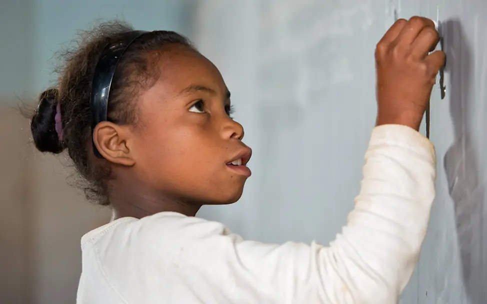UNICEF setzt sich für eine bessere Bildung in Afrika ein. | © UNICEF/Matas Schulen in Afrika: Ein Mädchen in Madagaskar schreibt mit Kreide an eine Tafel.