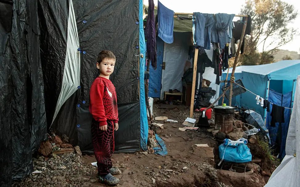In den Flüchtlingslagern herrschen schlimme Zustände. | © UNICEF/Romenzi Flüchtlingslager Griechenland: Ein Junge steht zwischen den Zeltunterkünften.