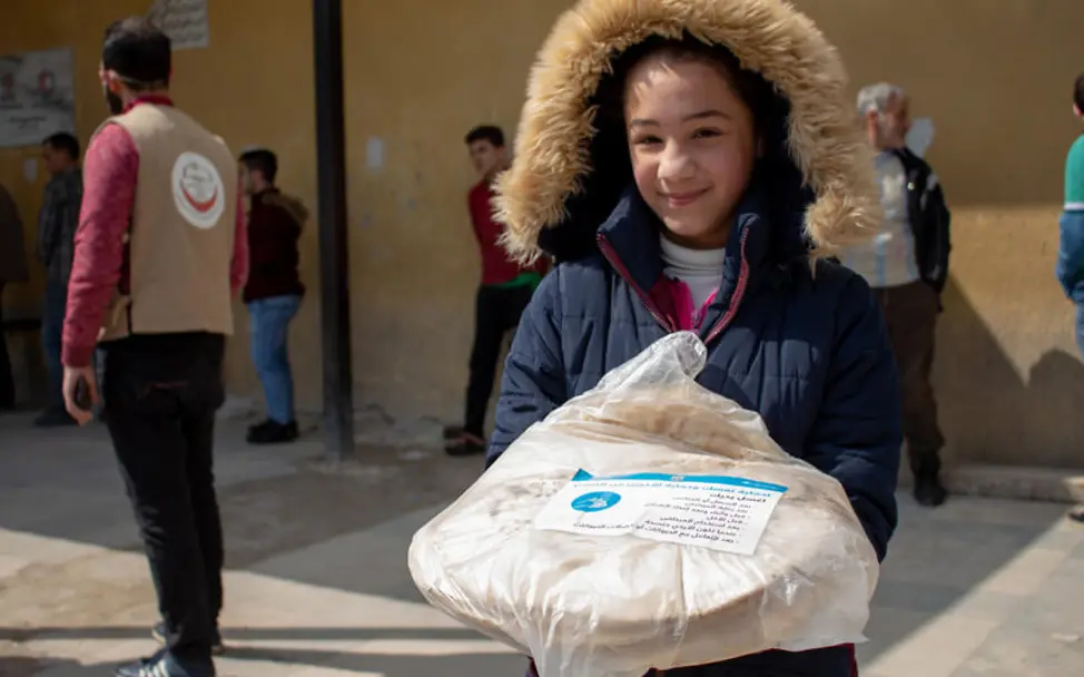 Syrien: Mädchen hält eine Tüte Brot mit einem Flyer zu Corona | © UNICEF Syrien: Mädchen hält eine Tüte Brot mit einem Flyer zu Corona