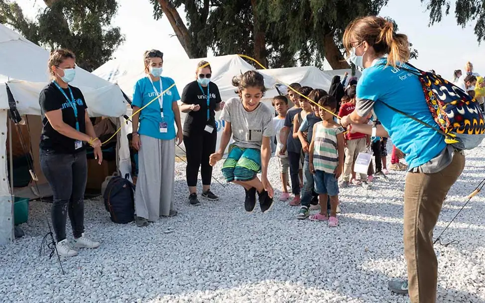 Beim Spielen können die Kinder einen Augenblick ein Stück Normalität erfahren. | © UNICEF/Canaj/Magnum Photos Lesbos: Kinder beim Seilchen springen mit UNICEF-Helfern