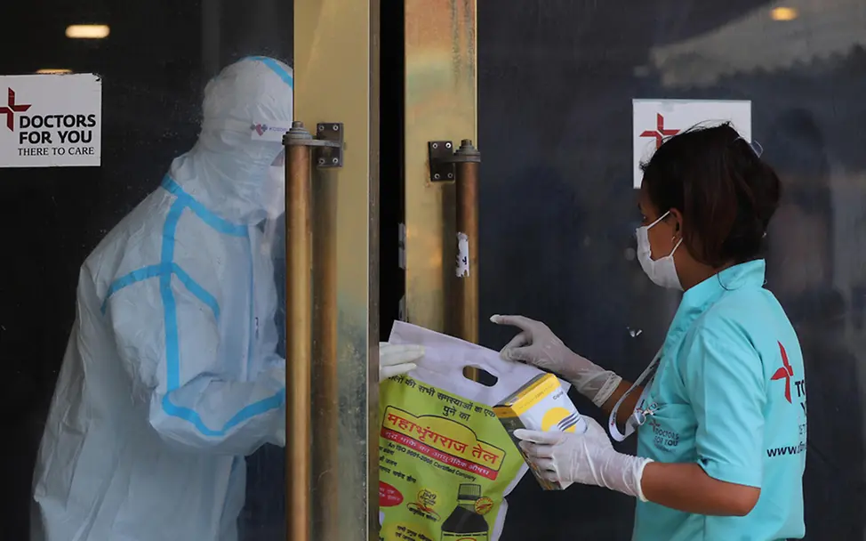 Corona Indien: Eine Gesundheitshelferin gibt einer Kollegin Schutzkleidung | © UNICEF/Singh Corona Indien: Eine Gesundheitshelferin gibt einer Kollegin Schutzkleidung