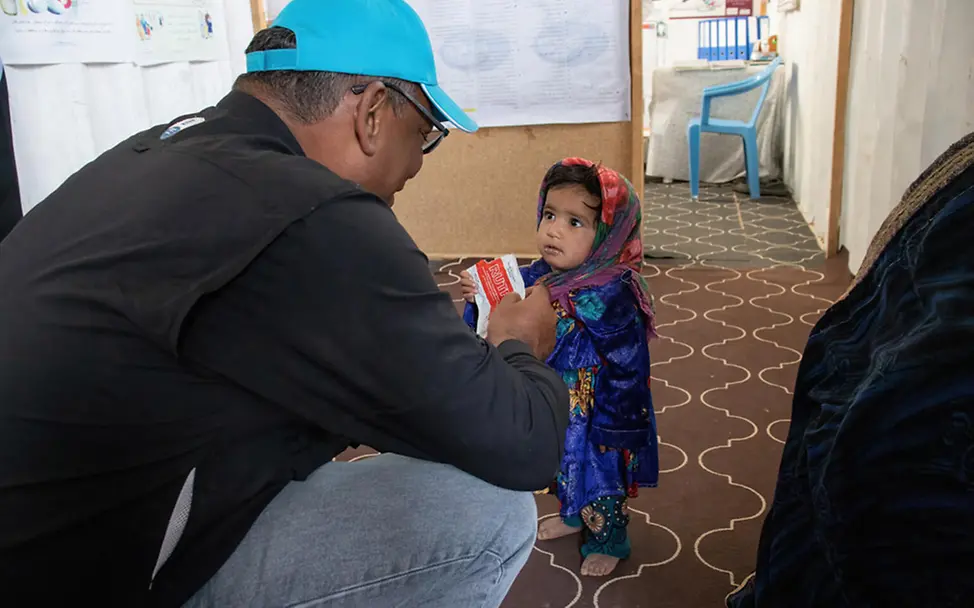 Hunger in Afghanistan: Ein UNICEF-Helfer gibt einem Mädchen Erdnusspaste | © UNICEF/Bidel Hunger in Afghanistan: Ein UNICEF-Helfer gibt einem Mädchen Erdnusspaste