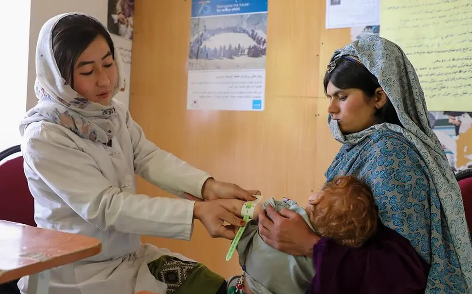 Hunger weltweit: Eine Ernährungshelferin in Afghanistan untersucht ein Kind und setzt sich so gegen den Welthunger ein.