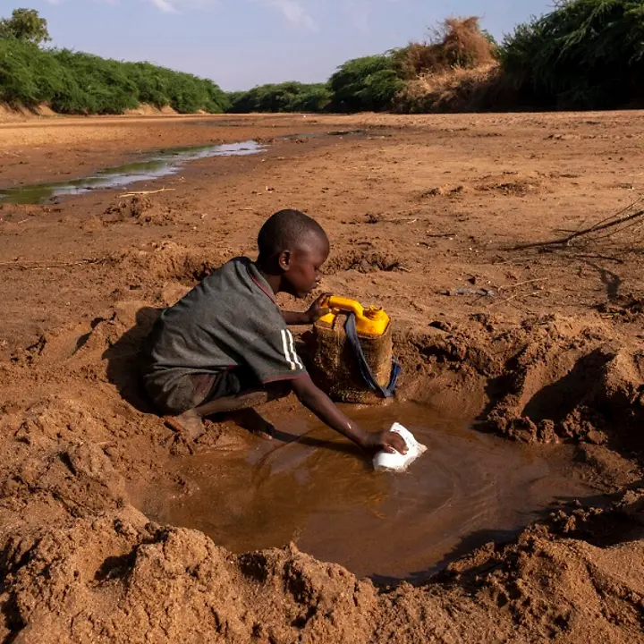 Somalia: Junge sammelt Wasser in einer Pfütze.