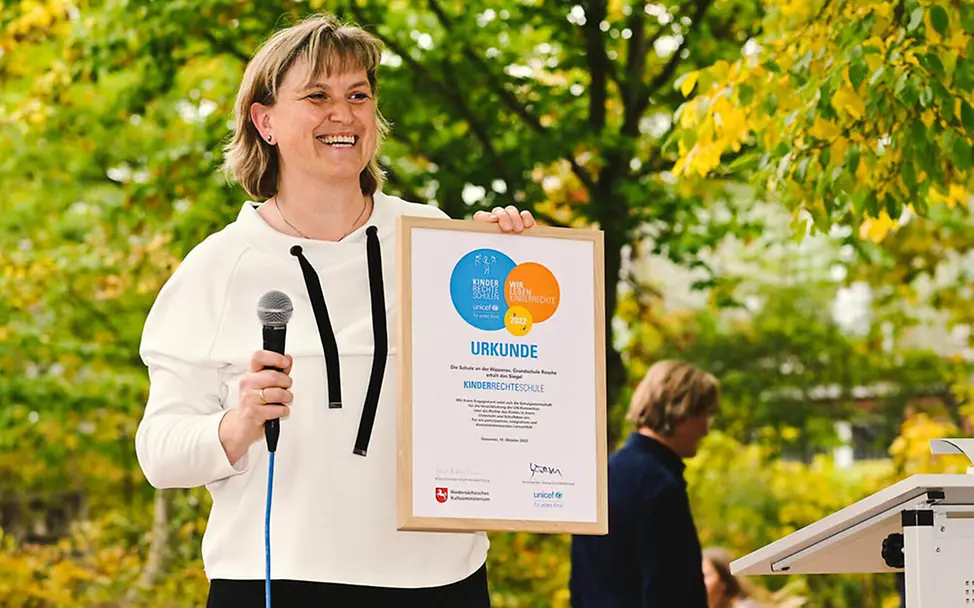 UNICEF-Kinderrechteschule: Schuldirektorin Susanne Prehm zeigt stolz die Urkunde | © UNICEF/Quittenbaum UNICEF-Kinderrechteschule: Schuldirektorin Susanne Prehm zeigt stolz die Urkunde