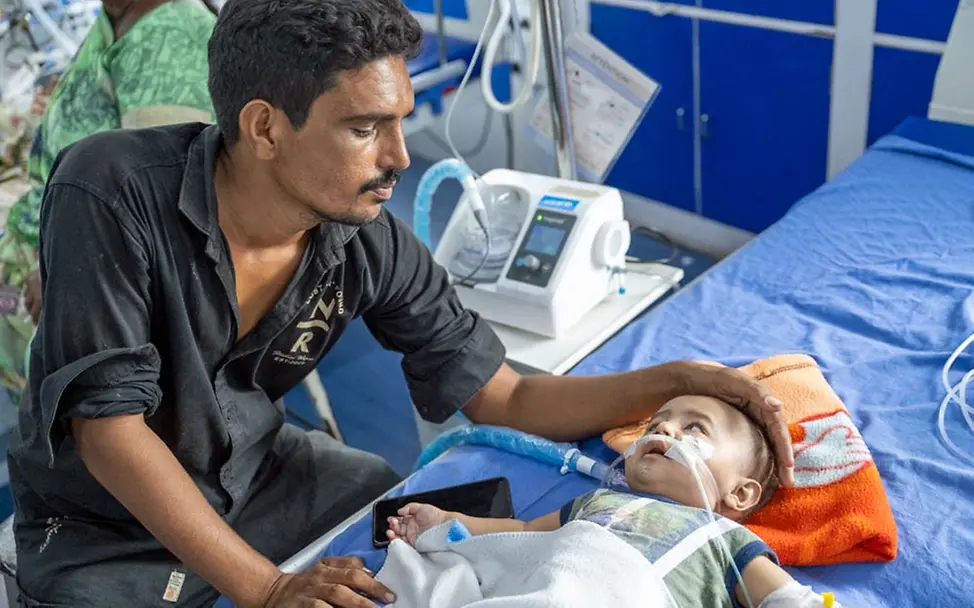 Ein Vater beobachtet sein Baby, das im Krankenhaus mit Sauerstoff versorgt wird. | © UNICEF/Panjwani Gesundheitshilfe für Kinderstationen: UNICEF stattet Krankenhäuser mit medizinischem Equipment aus.