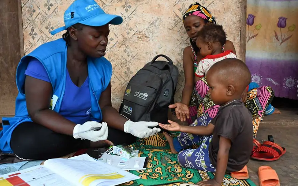 Malaria: Eine UNICEF-Mitarbeiterin führt bei einem Jungen einen Malaria-Schnelltest durch.