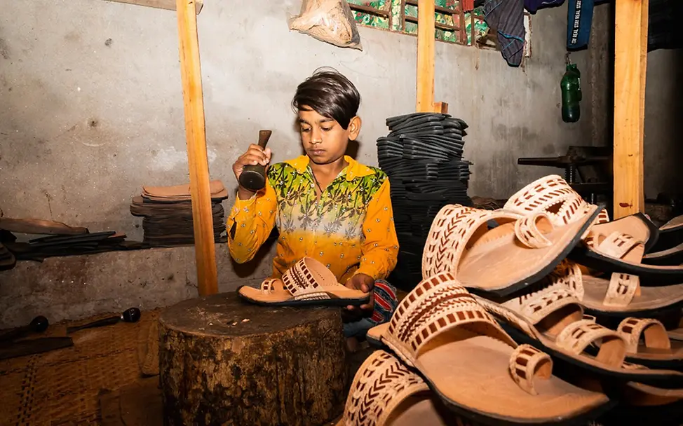 Was kann man gegen Kinderarbeit tun: Ein Junge stellt in einer Werkstatt in Bangladesch Sandalen her. 