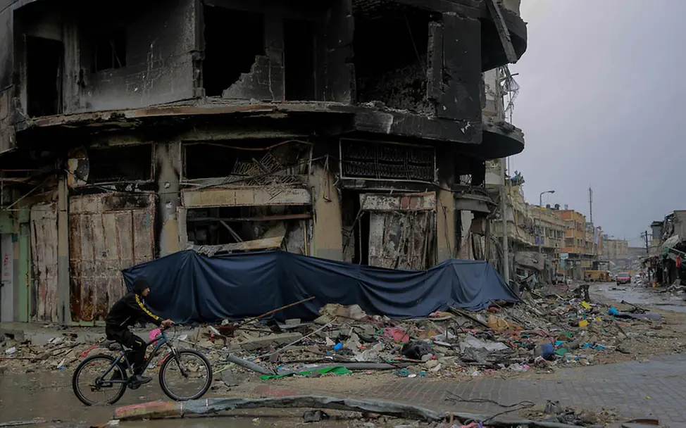 Kinder in Gaza: Ein Junge fährt auf seinem Fahrrad an einem völlig zerstörten Wohnhaus vorbei | © UNICEF/Al-Qattaa Gaza Kinder: Ein Junge fährt auf seinem Fahrrad an einem völlig zerstörten Wohnhaus vorbei