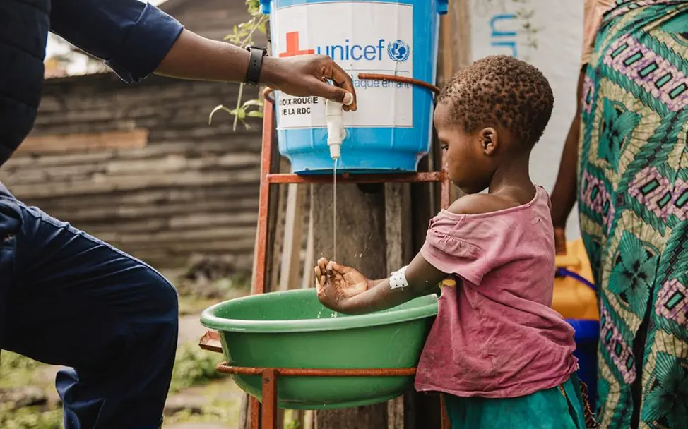 Hygieniker desinfiziert Mädchenhände im Afya Sake CTC, Nord-Kivu, DR Kongo. | UNICEF/Benekire Hygieniker desinfiziert Mädchenhände im Afya Sake CTC, Nord-Kivu, DR Kongo.