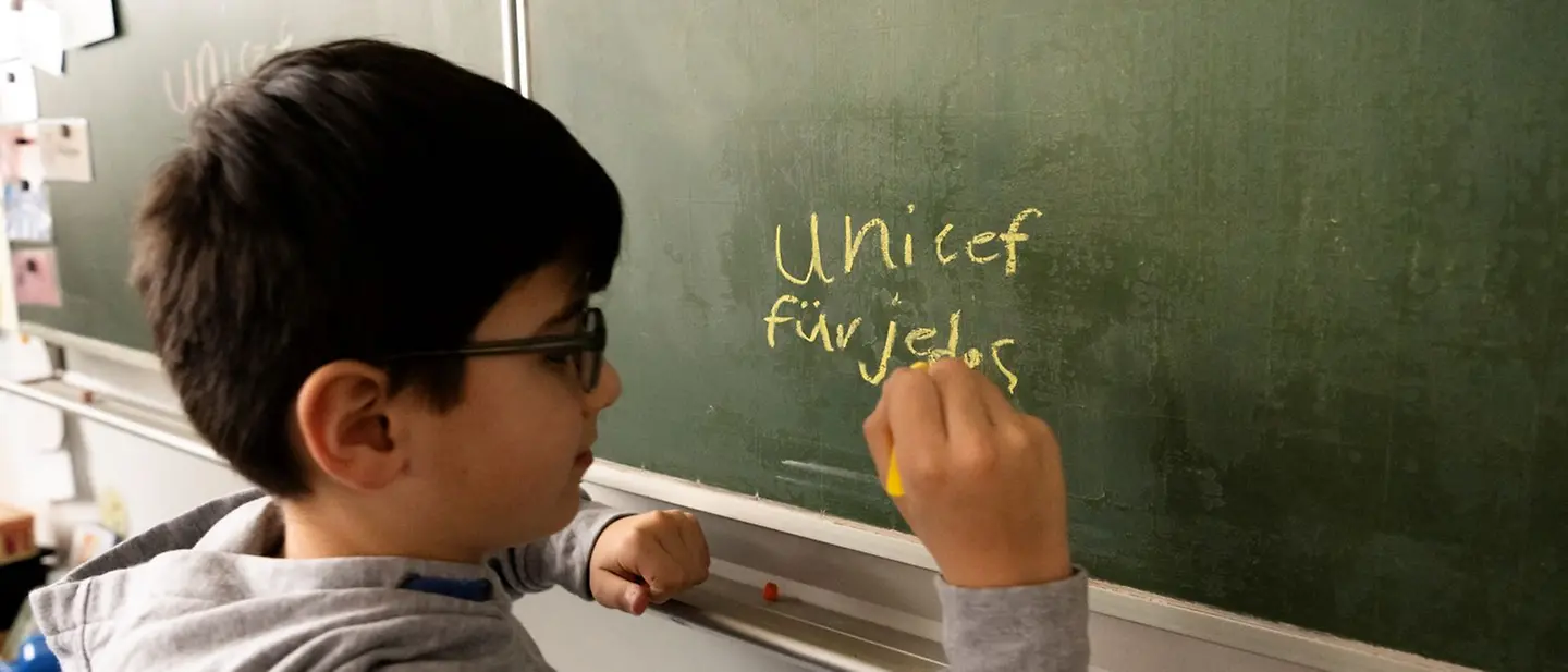 Anmeldung zum Programm | © UNICEF/UNI503884/Etges Ein Junge schreibt an die Tafel. Seine Klasse nimmt an der UNICEF-Spendenaktion "Lesen für UNICEF" teil.