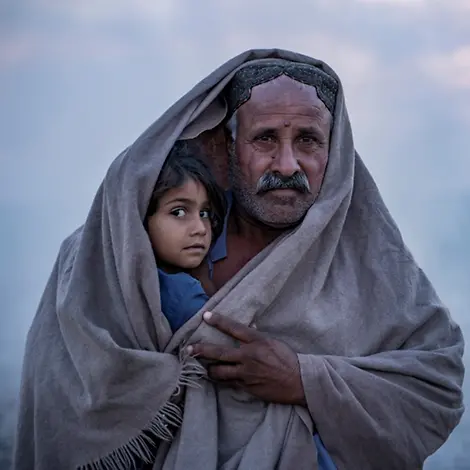 Hasol Khan bedeckt sich und seine Tochter vor seinem Zelt im Dorf Zangi Brohi in Sindh, mit einem Schal. | © UNICEF/UN0761219/Butt Weltflüchtlingstag: Hasol Khan bedeckt sich und seine Tochter vor seinem Zelt im Dorf Zangi Brohi in Sindh, mit einem Schal.