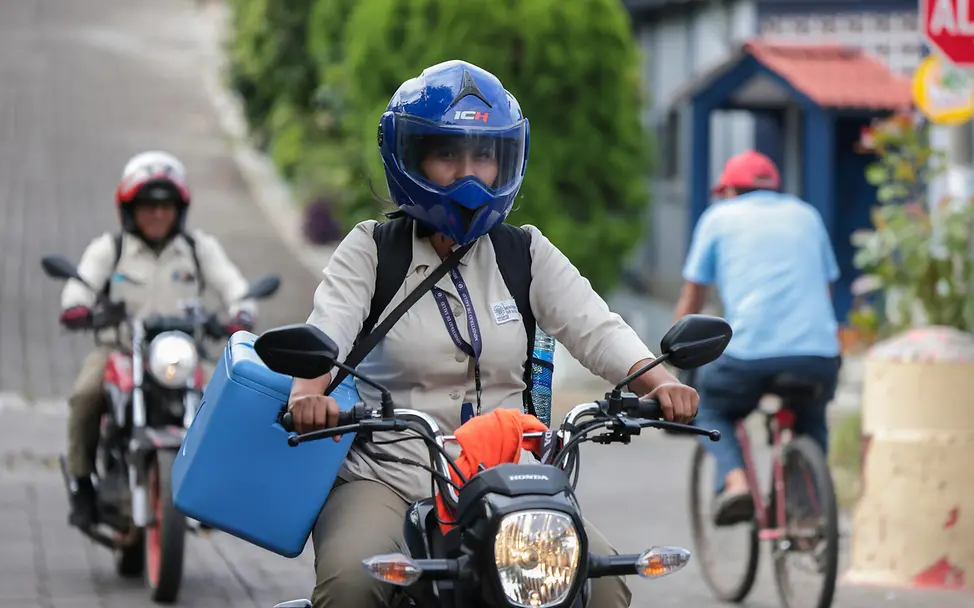 El Salvador: Glenda fährt mit ihrer Kühlbox voller Impfungen Motorad.