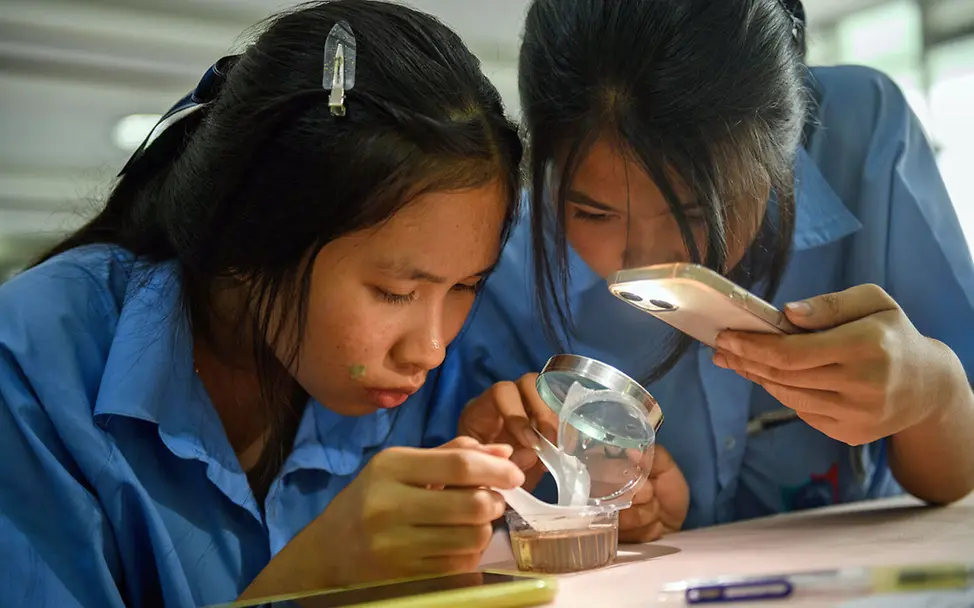 Malaria Kinder schützen: Zwei Schülerinnen in Thailand untersuchen Mückenlarven. 
