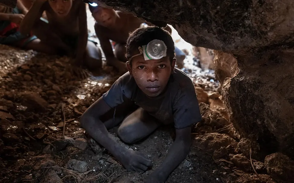 Was kann man gegen Kinderarbeit tun: Ein Junge hockt mit einer Stirnlampe in einer Glimmermine in Madagaskar.