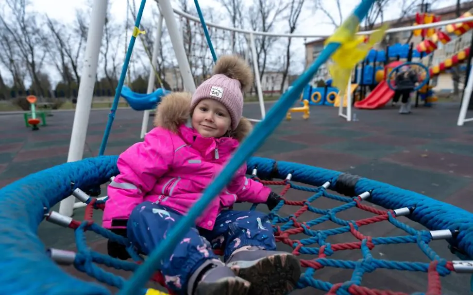 UNICEF unterstützt Maßnahmen zum Wiederaufbau. | © UNICEF/Filippov Ukraine: Ein Mädchen sitzt in einer Schaukel.