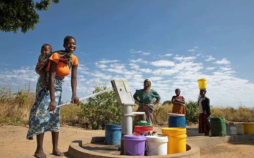 Sambia Wasser: Eine Frau pumpt an einer Wasserstelle Wasser in einen Eimer. 