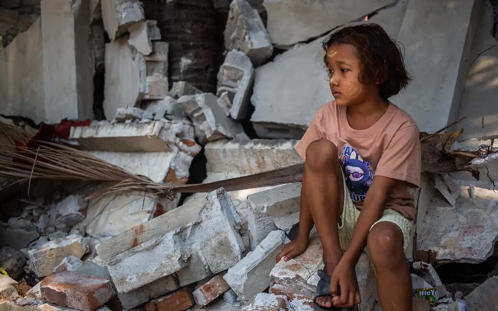 Ein Mädchen sitzt nach dem Erdbeben in Myanmar auf Trümmern in Mandalay.
