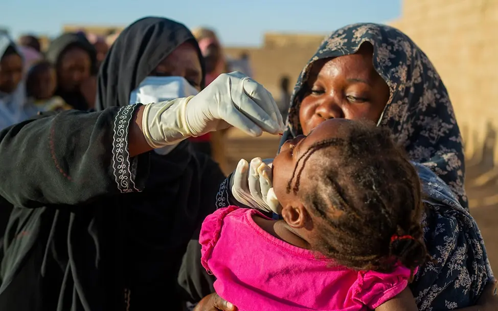 Sudan Spenden: Ein Kleinkind bekommt von einer Gesundheitshelferin eine Dosis Vitamin A