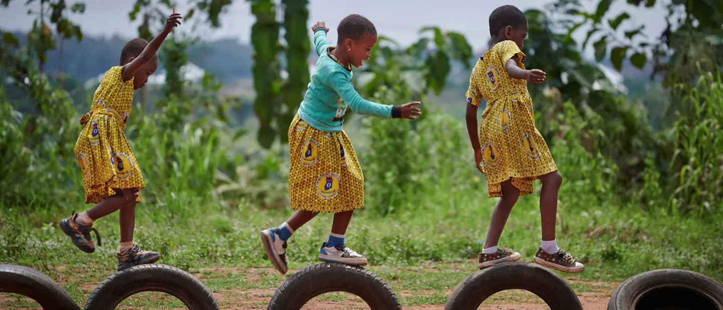 Mädchen hüpfen auf einem Spielplatz der Atia Methodist Primary School in der Region Ashanti in Ghana auf Reifen.