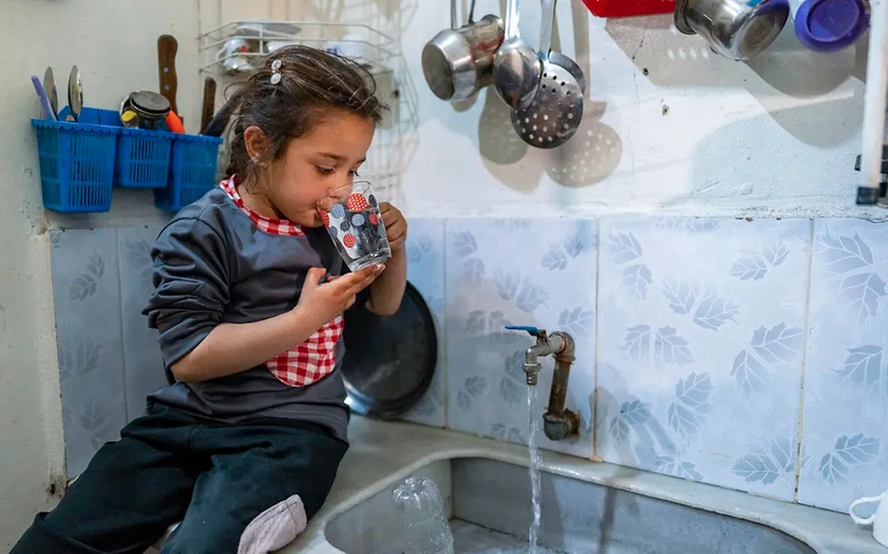 Sahar (6) trinkt in der Küche ein Glas Wasser.
