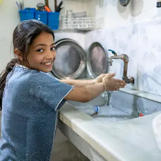 Fatima, 11 wäscht sich glücklich die Hände.