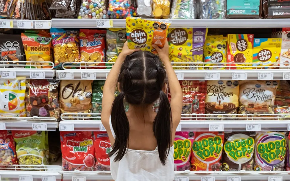 Kinder Ernährung: Micaella (8) greift im Supermarkt zu den Süßigkeiten.