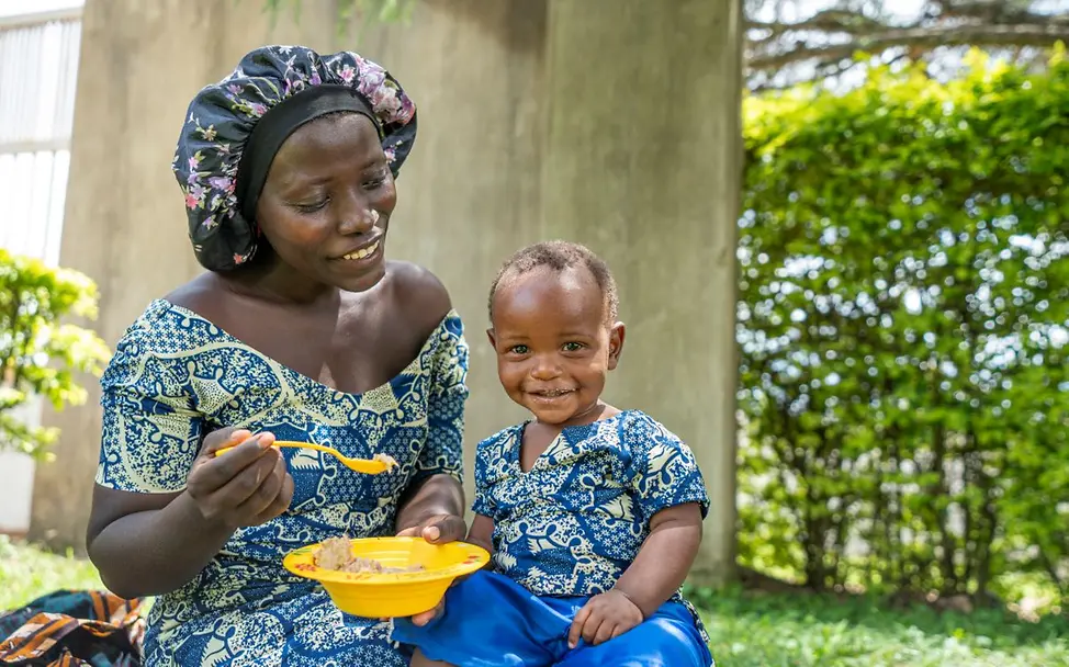 Eine Mutter füttert ihr einjähriges Kind in Uganda. Hilfsgüter wie Lebensmittel sind für kleine Kinder besonders wichtig.