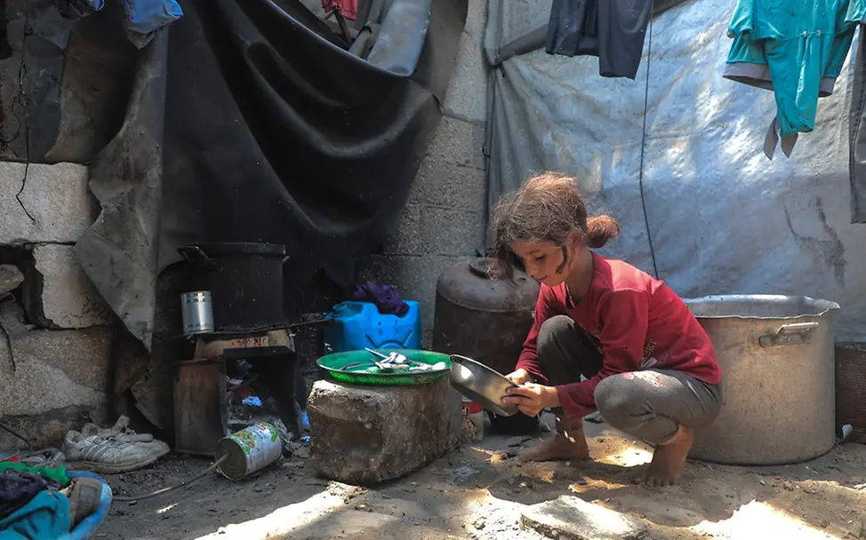 Kinder in Gaza: Ein Mädchen sitzt an einer Kochstelle in einer Notunterkunft