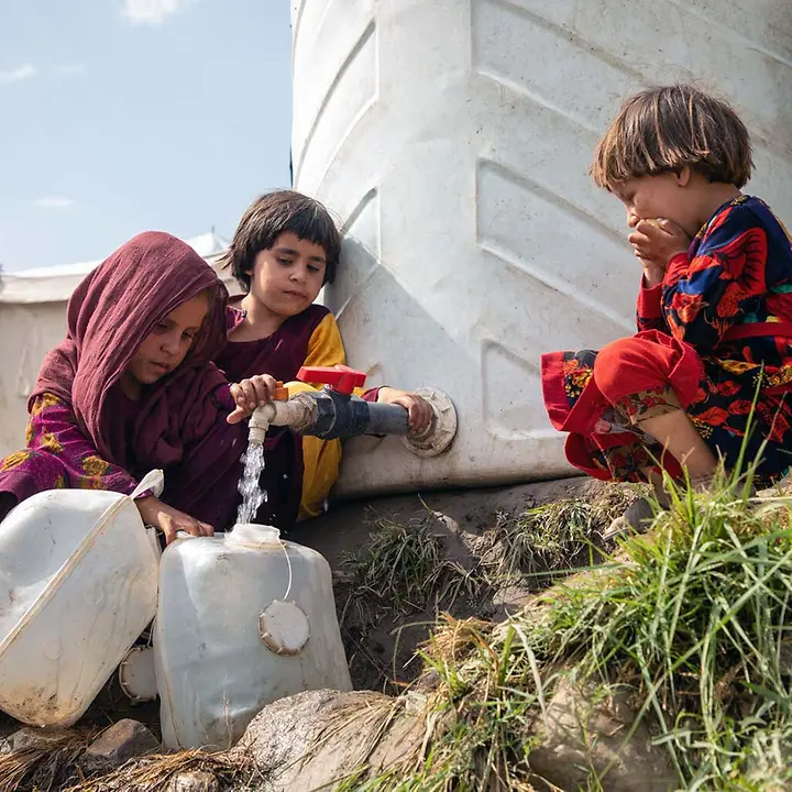 Afghanistan Nothilfe spenden: Kinder in einem Flüchtlingscamp füllen Wasser in Kanister ab. 
