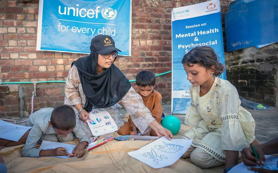 Monsun Nothilfe: Eine Psychologin in Pakistan gibt von Überschwemmungen betroffenen Kindern Bilder zum Ausmalen. 