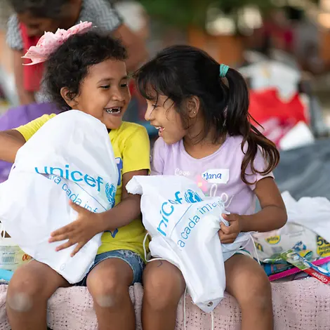 Spenden für den guten Zweck: Mit Ihrer Spende erreicht UNICEF Kinder auf der ganzen Welt. | UNICEF/Marin Originelle Geschenkideen für den guten Zweck: Zwei Mädchen packen lachend ihre UNICEF-Beutel aus.