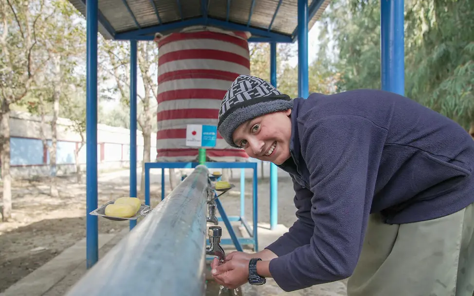 Schenken für den guten Zweck: UNICEF unterstützt mit Ihrer Spende die Versorgung mit sauberem Trinkwasser. | © UNICEF/Karimi Originelle Geschenkideen für einen guten Zweck: Ein Junge trinkt Wasser aus einer Wasserleitung im Freien.