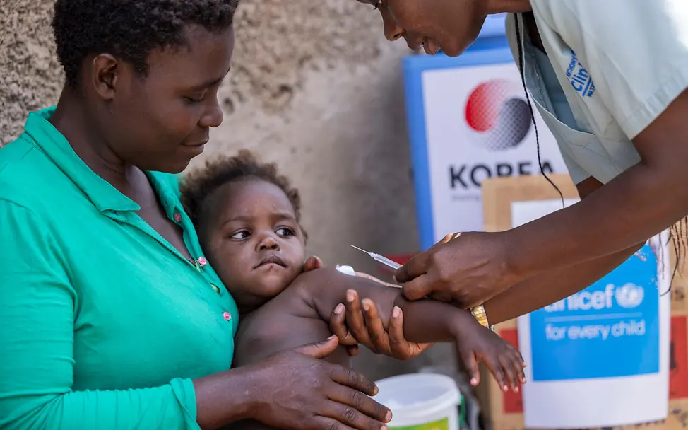 Geschenke für den guten Zweck: Geldspenden an UNICEF unterstützen den Kauf von Spezialnahrung, Medikamenten und zahlreichen anderen Hilfsgütern für Kinder. | © UNICEF/Watsemba Originelle Geschenkideen für den guten Zweck: Eine UNICEF-Helferin impft ein Baby auf dem Schoß seiner Mutter.