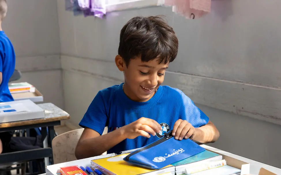 Schenken für den guten Zweck: Lernmaterialien, Bücher und Schulrucksäcke helfen Kindern zu lernen und ihre Chancen zu verbessern. | © UNICEF/Izhiman Originelle Geschenkideen für einen guten Zweck: Ein Schüler schaut sich im Klassenraum seine neuen Schulmaterialien an.