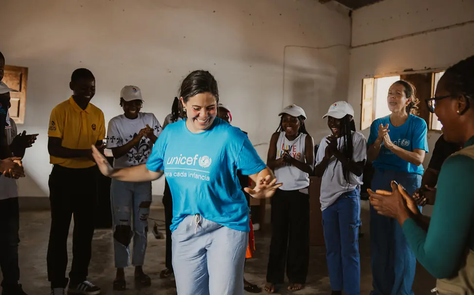Schenken für den guten Zweck: Schenken Sie mit Ihrer Spende Freude und Hoffnung für Kinder weltweit. Originelle Geschenkideen für einen guten Zweck: Eine UNICEF-Helferin tanzt mit Jugendlichen in Mosambik.