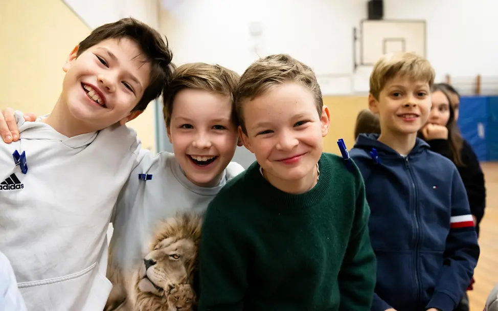 Schenken für den guten Zweck: Etwas Gutes zu bewirken, macht glücklich. | © UNICEF/Etges Originelle Geschenkideen für einen guten Zweck: Vier Jungen in einer Schulsporthalle lächeln in die Kamera.