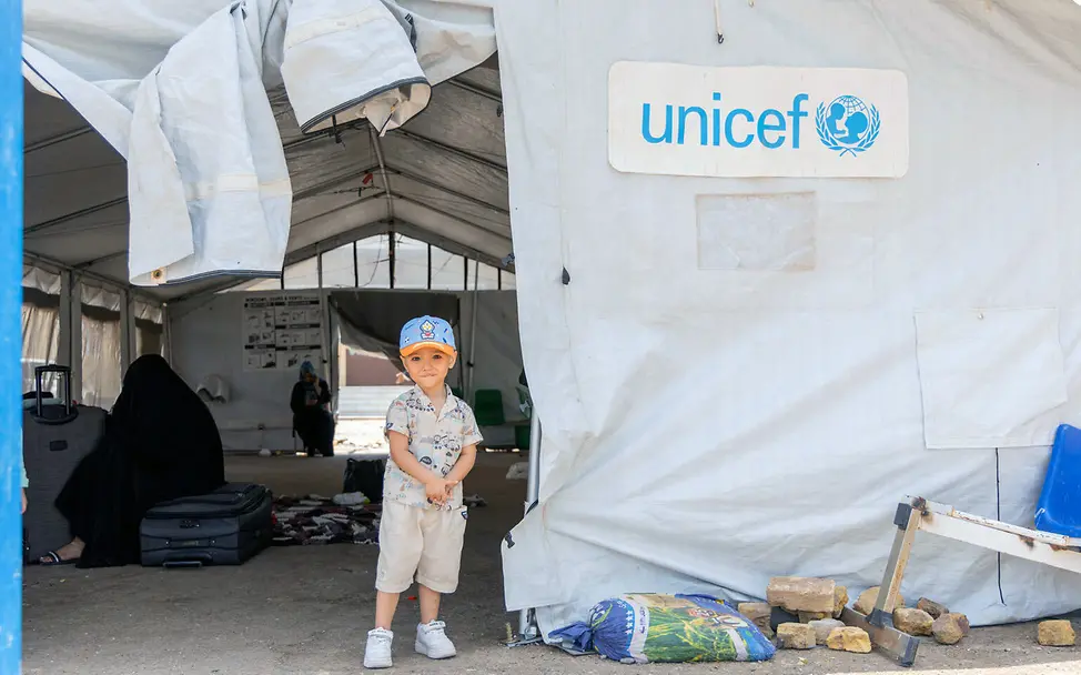 Spenden Nothilfe: Ein geflüchteter Junge in Afghanistan steht vor einem großen UNICEF-Kinderschutz-Zelt