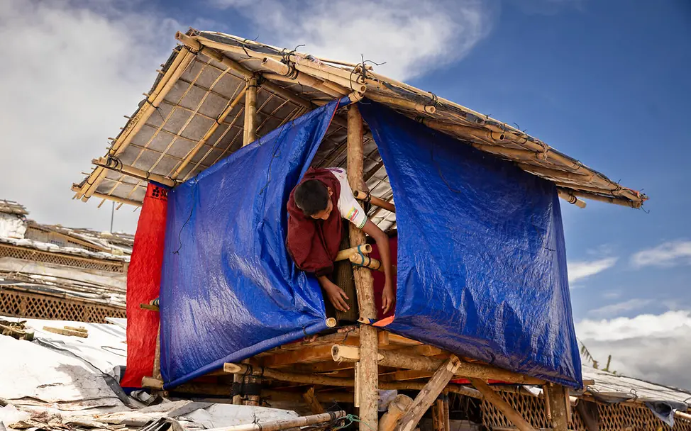 Rohingya in Bangladesch: Die einfachen Hütten im Camp können Regen und Wind kaum standhalten. | © UNICEF/Njiokiktjien Rohingya Flüchtlingslager: Ein Junge befestigt eine Plane an seiner Hütte.