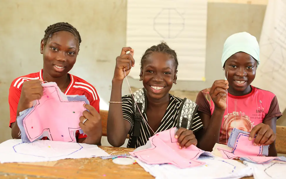 Periodenarmut: Bei Schulprojekten lernen Mädchen, Stoffbinden zu nähen, damit ihre Periode sie nicht einschränkt. | © UNICEF/Keïta Was ist Periodenarmut: Drei Mädchen nähen Stoffbinden.