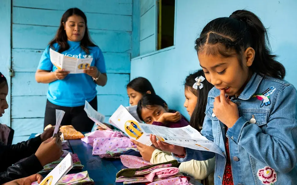 Periodenarmut: In der Schule können Mädchen schon früh Fakten über die Menstruation lernen. | © UNICEF/Izquierdo Was ist Periodenarmut: Mädchen und ihre Lehrerin schauen sich Menstruations-Sets an.