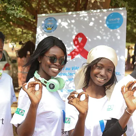 AIDS einfach erklärt: Vier Engagierte für U-Report posieren vor einem Plakat.